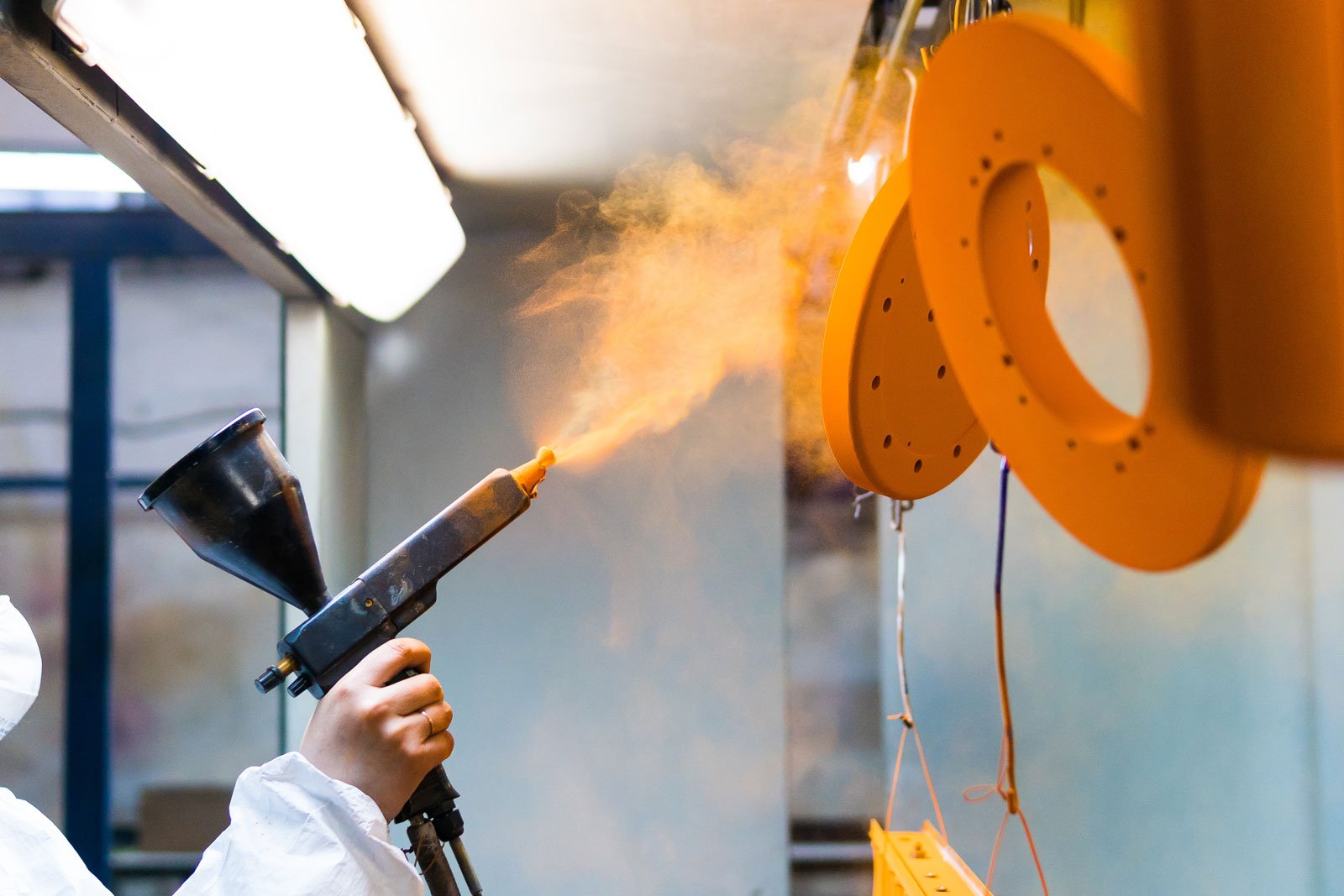 Powder Coating of Metal Parts. a Woman in a Protective Suit Sprays Powder Paint from a Gun on Metal Products